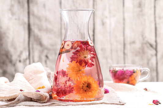 a big glass of flower tea chrysanthemum red dates chamomile stand on a table with grey background