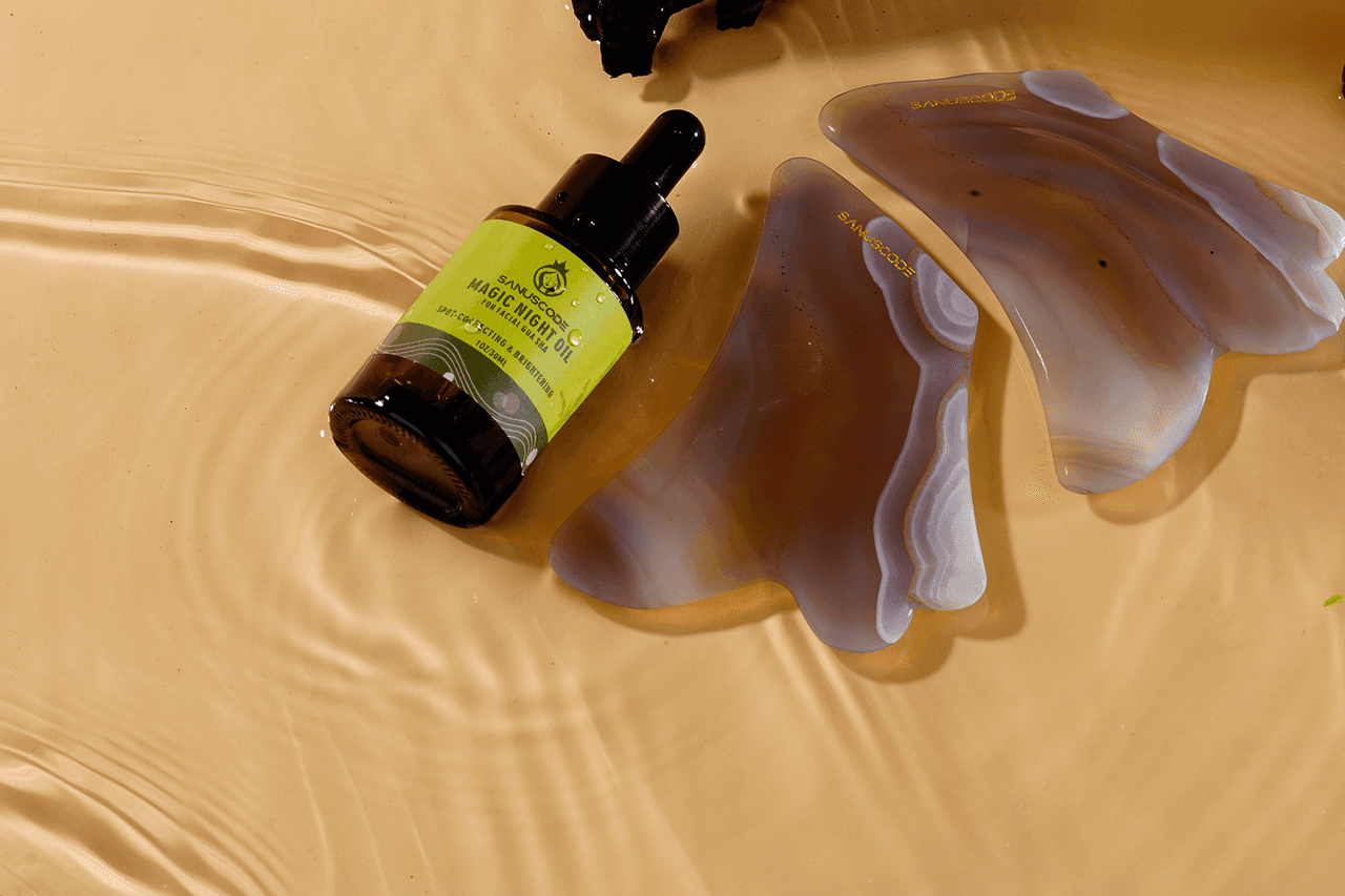 brown bottle of facial gua sha oil and agate gua sha stone float on water, beige background