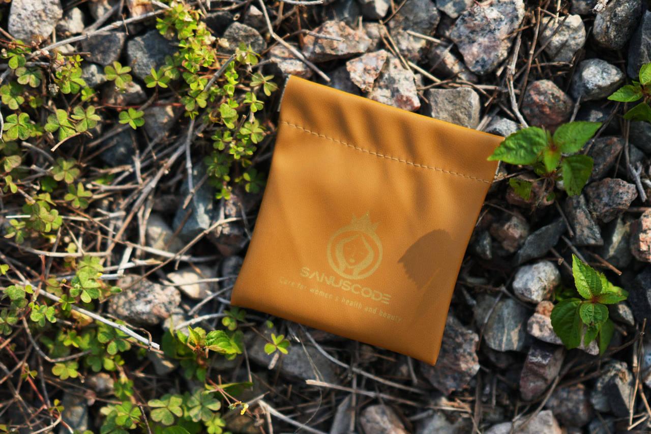 small orange pu leather gua sha stone pouch lay on small gravels at the sunset